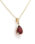 Necklace with a pear shaped garnet pendant bezel set on a white background