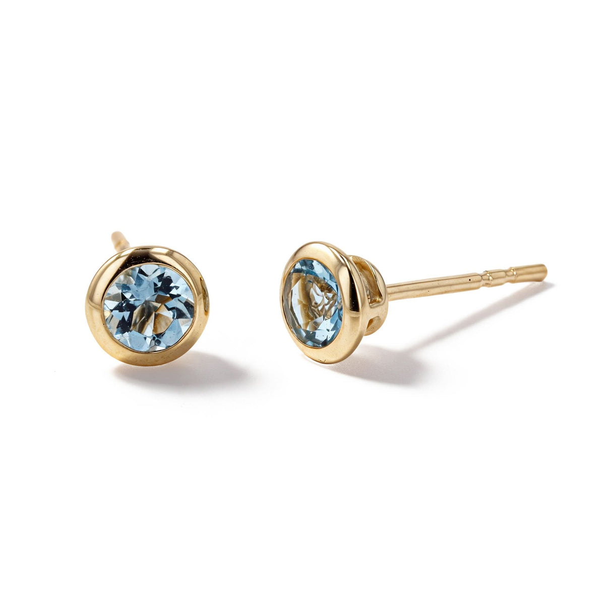 A pair of gold stud earrings with round-cut light blue gemstones, shown on a clean white background.