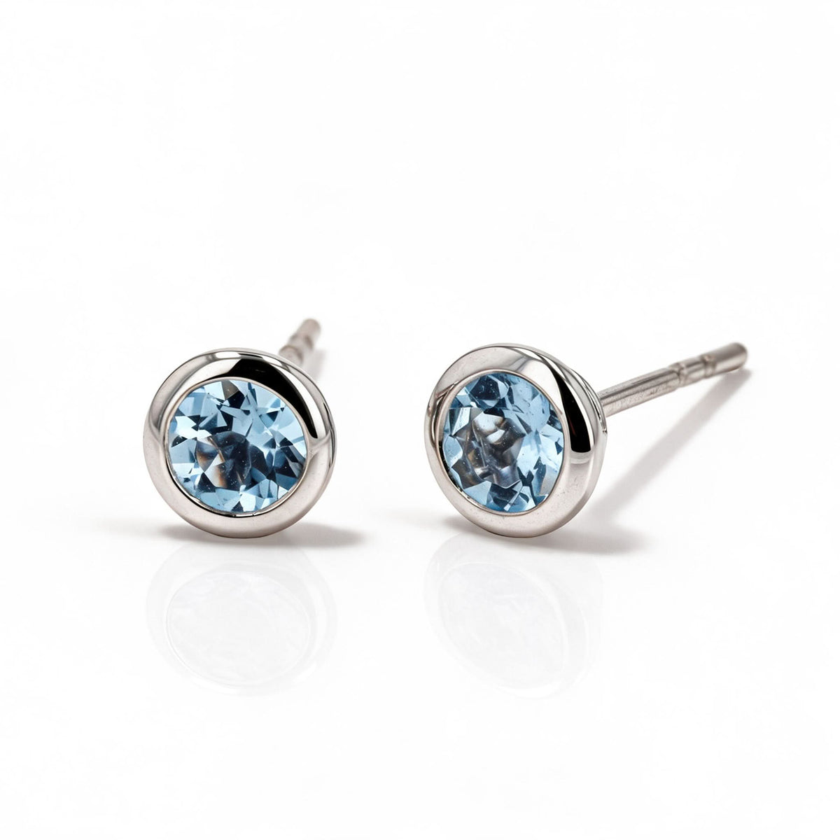 Pair of blue gemstone earrings with white gold bezels on a white background