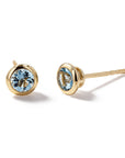 A pair of gold stud earrings with round-cut light blue gemstones, shown on a clean white background.