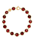 A gold link bracelet featuring ten faceted deep red gemstones in bezel settings, arranged in a circle on a light off-white background.