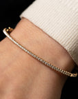 Gold bracelet with diamonds on a wrist against a black background