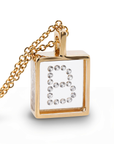A gold pendant with a square pendant featuring a clear  diamond-enclosed letter 'B' on a white background, shown on a clean white studio background.