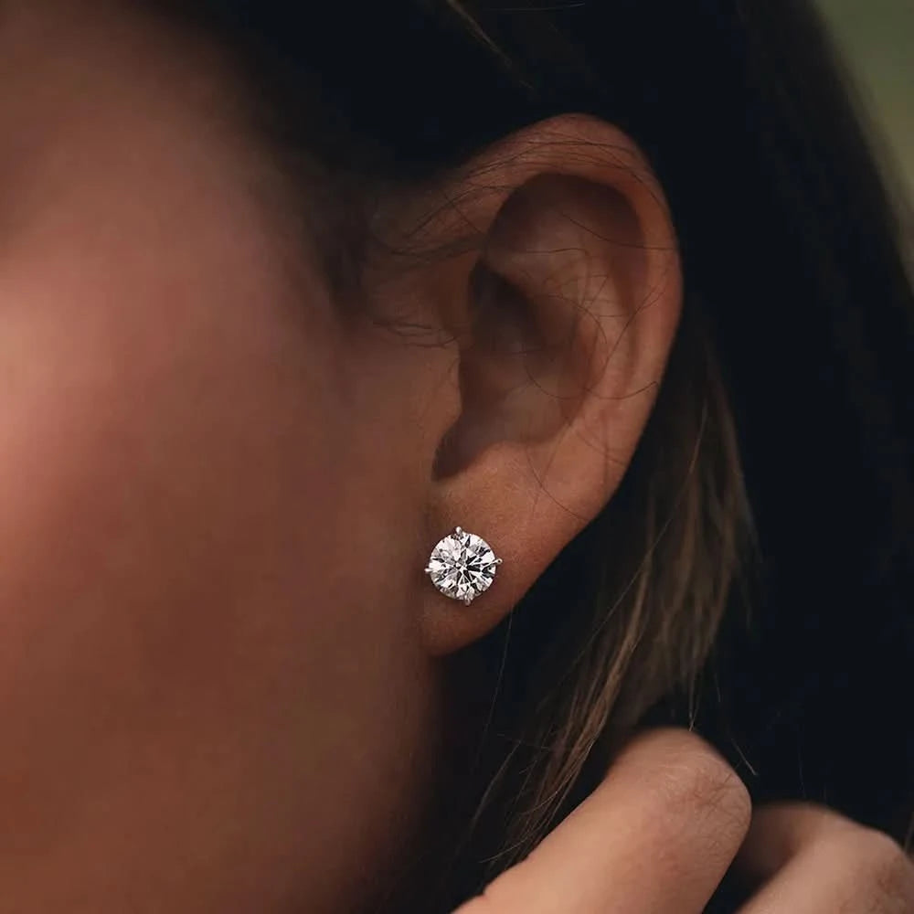 Close-up of a lab diamond stud earring on an ear with a blurred background