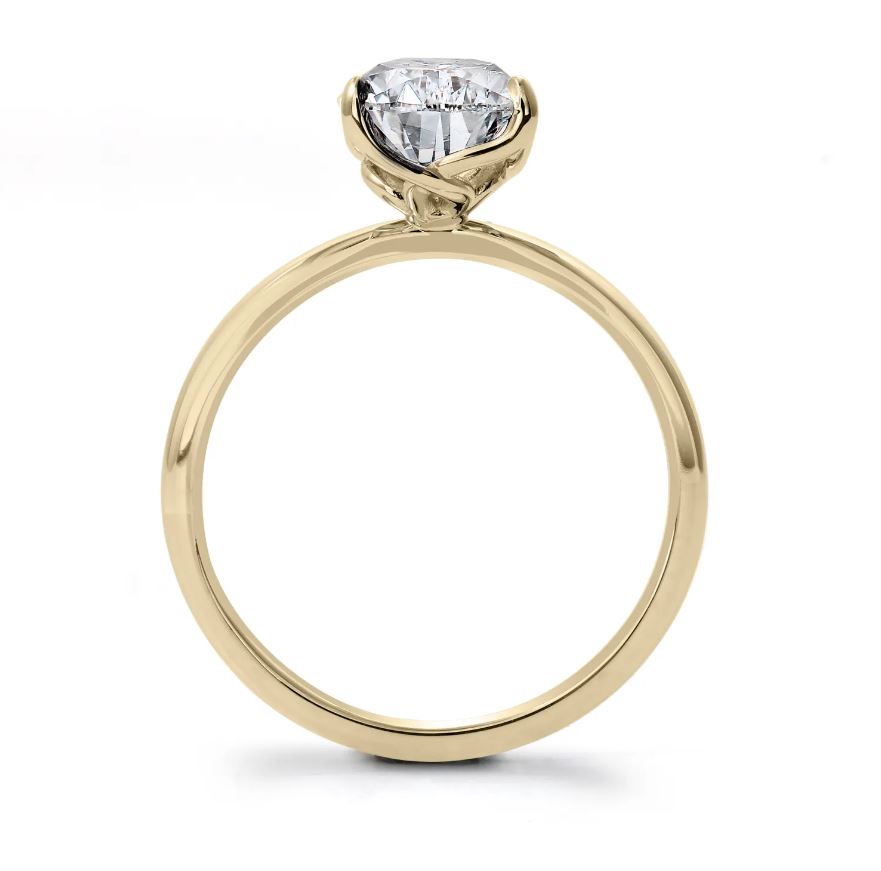 Gold ring with a lab grown pear shape diamond on a white background- side view