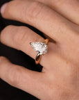 yellow gold ring with a pear-shaped lab grown diamond on a hand against a dark background