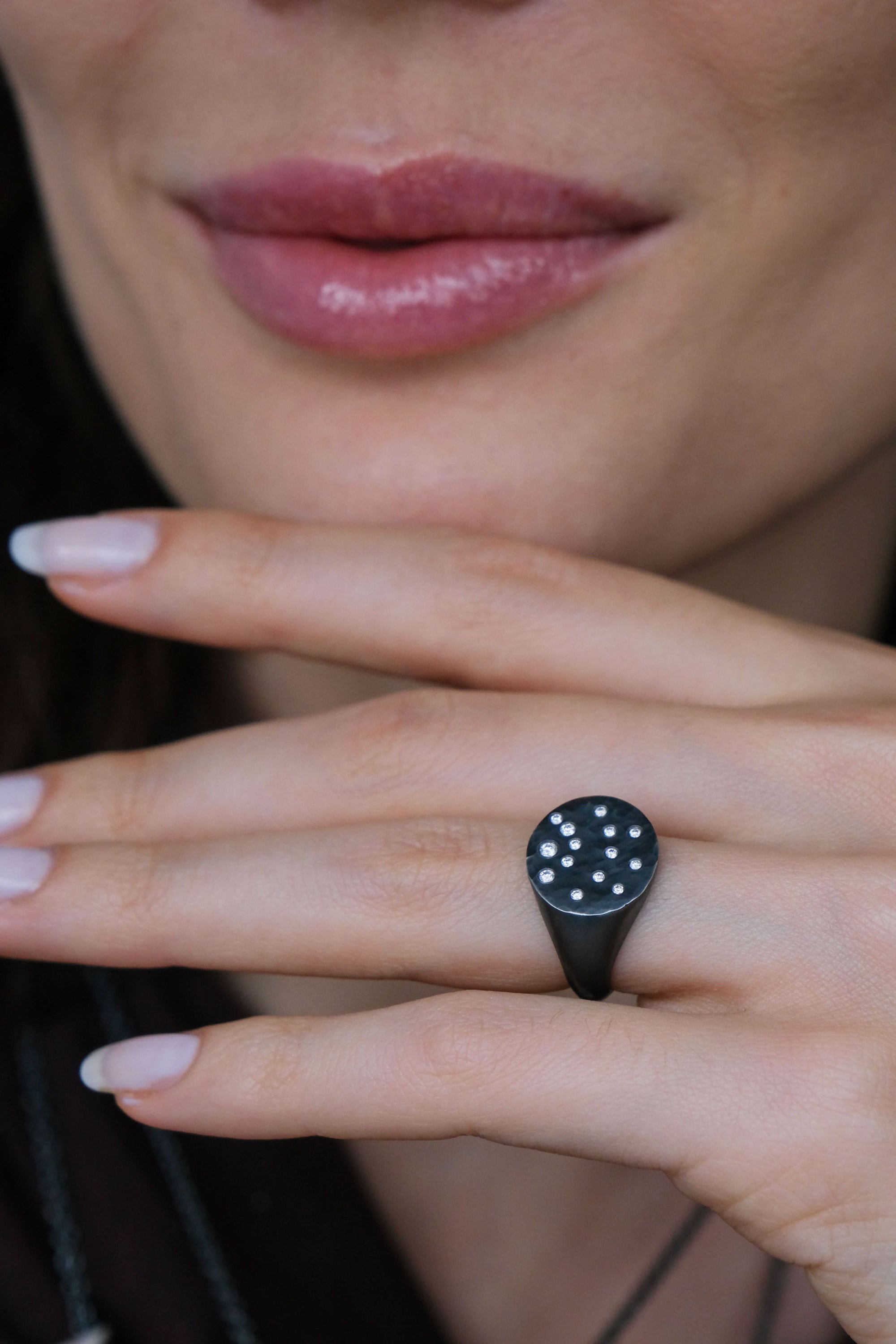 close up of hand wearing black ring with embedded diamonds
