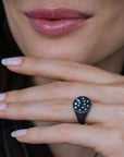 close up of hand wearing black ring with embedded diamonds