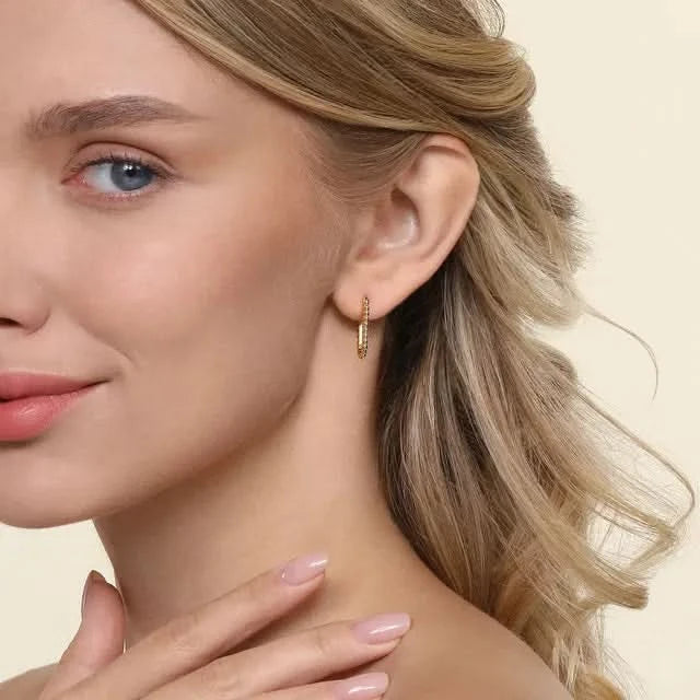Close-up of a woman wearing a gold hoop earring on a beige background