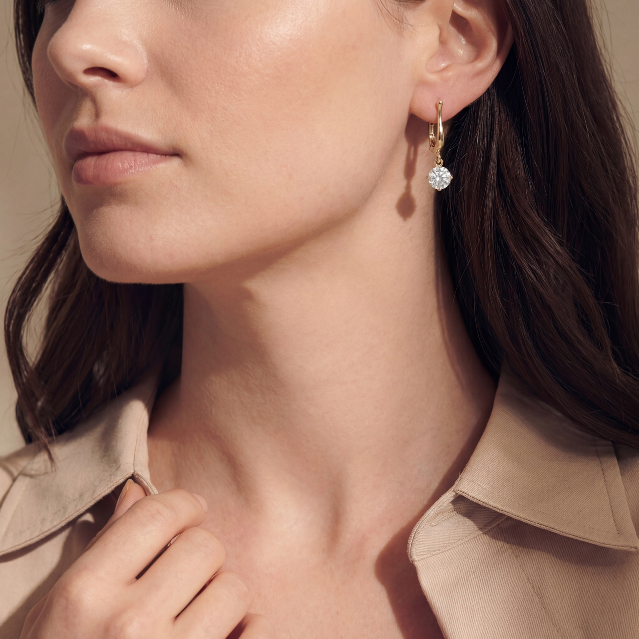Close-up of a woman wearing gold earrings with a neutral background