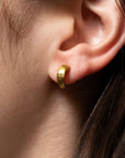 gold half drum stud earrings by Lika Behar modeled on an ear.