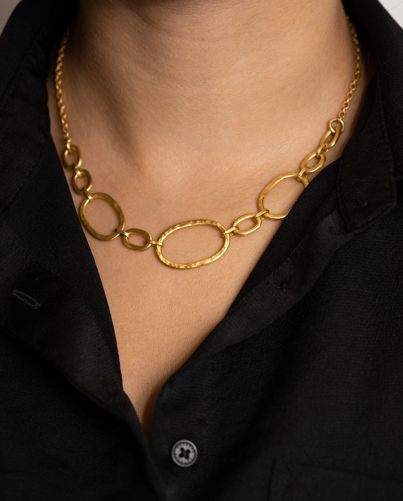 Close up of person wearing gold circular  chain necklace