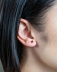 person wearing a white gold and garnet stud in their ear