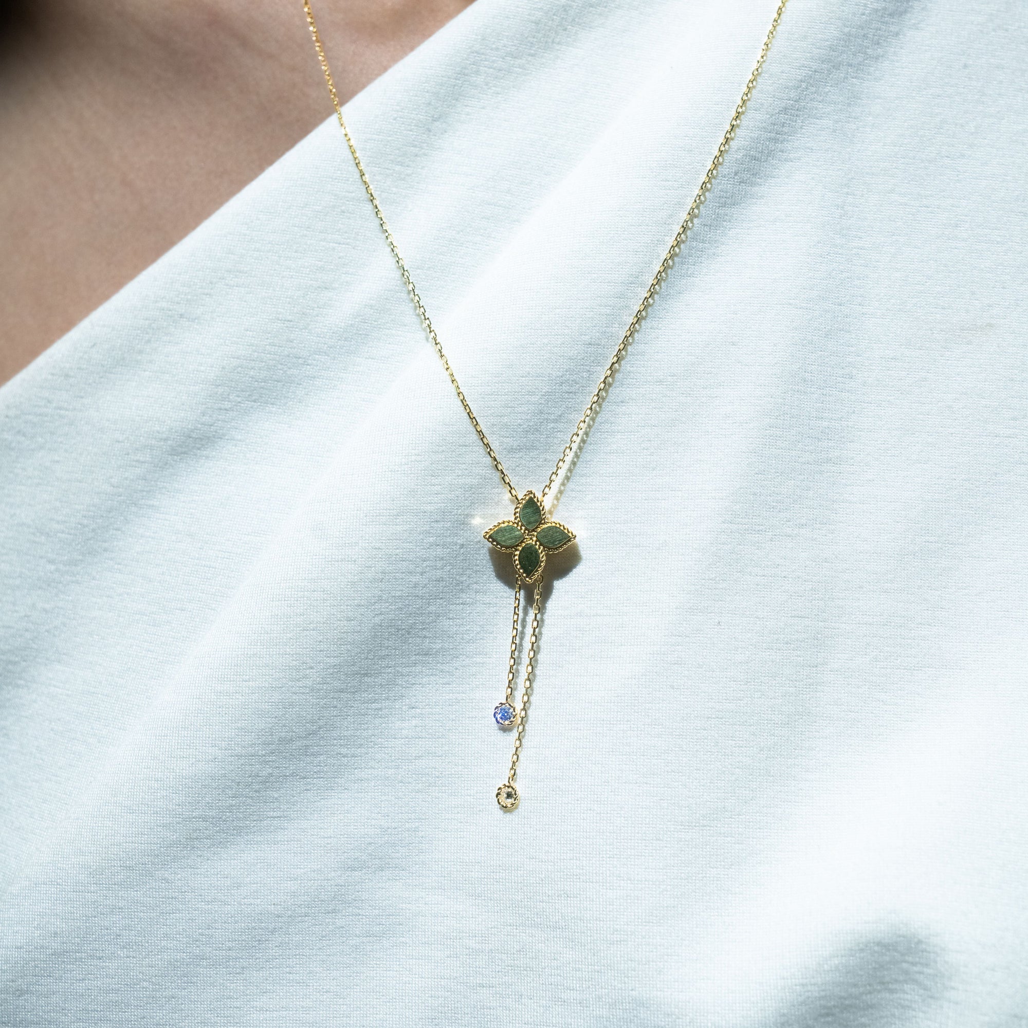 Gold necklace with a yellow gold pendant with diamond dangles on a white background