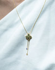 Gold necklace with a yellow gold pendant with diamond dangles on a white background