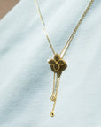 Gold necklace with a floral pendant on a light blue fabric background