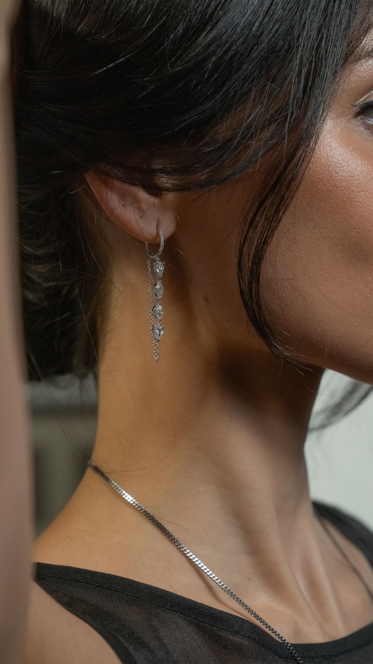 woman wearing a white gold huggie with multi shaped diamonds and chain