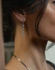woman wearing a white gold huggie with multi shaped diamonds and chain