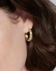 person wearing yellow gold hoop with embedded stones