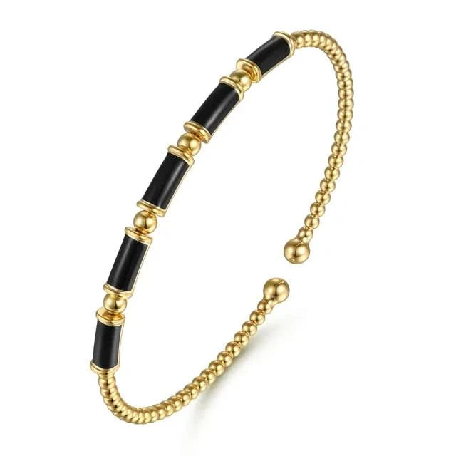 Gold and black beaded bracelet on a white background angled
