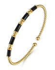 Gold and black beaded bracelet on a white background angled