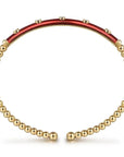 Gold beaded bracelet with a red enamel bar on a white background side view