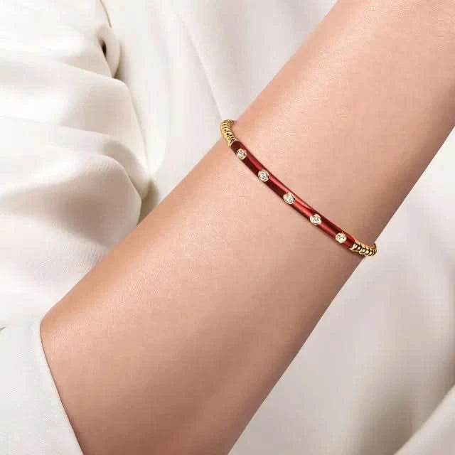 Red bracelet with gold accents on a person's wrist against a white background