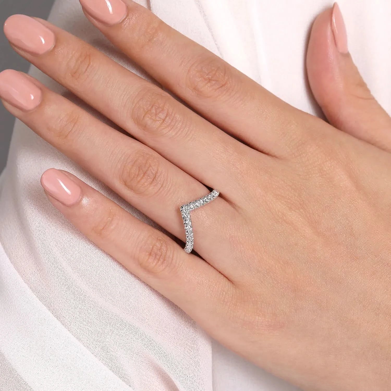 white gold diamond V-shaped ring on a hand with a white background
