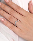white gold diamond V-shaped ring on a hand with a white background