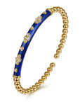 Gold bracelet with blue section and embedded stones on a white background angled