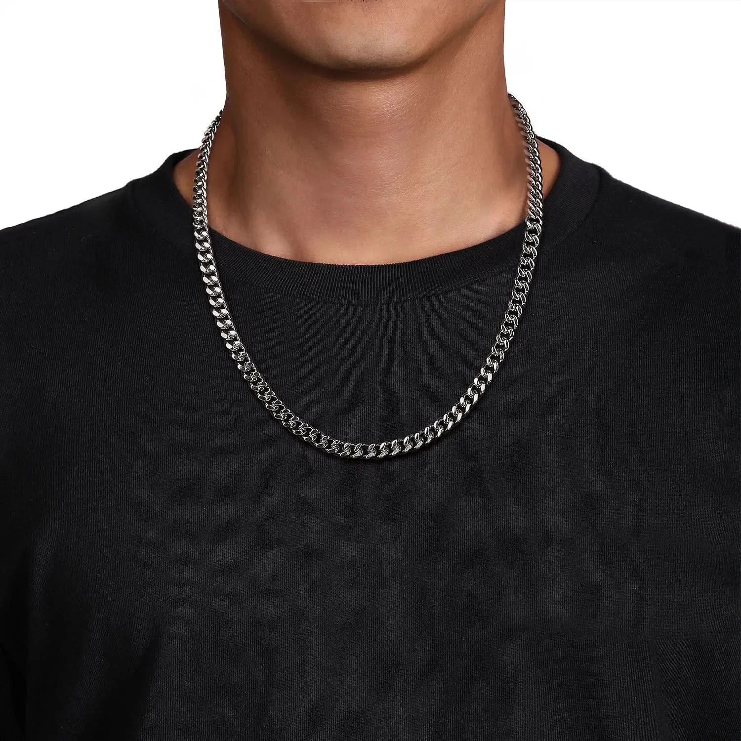 Person wearing a silver chain necklace against a black background