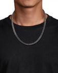 Person wearing a silver chain necklace against a black background
