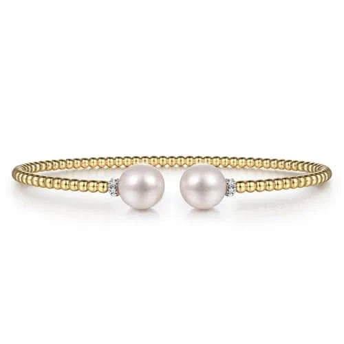 Gold bracelet with two pearls on a white background