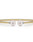Gold bracelet with two pearls on a white background