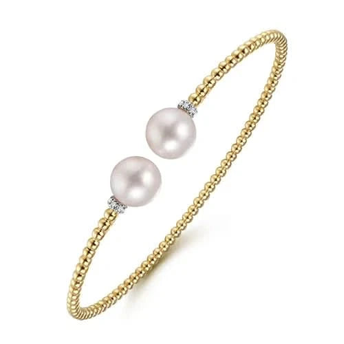 Gold bracelet with two  pearls on a white background angled
