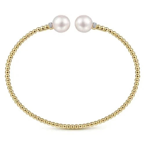 Gold bracelet with two pearls on a white background side view