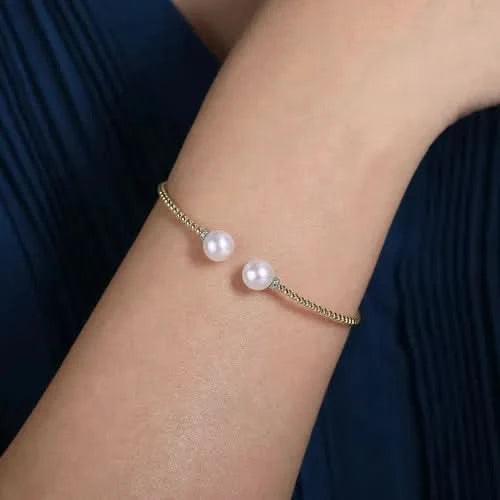 Pearl bracelet on a wrist with a dark blue fabric background
