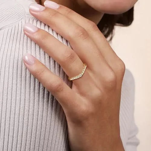 hand wearing curved yellow gold and diamond band on neutral background