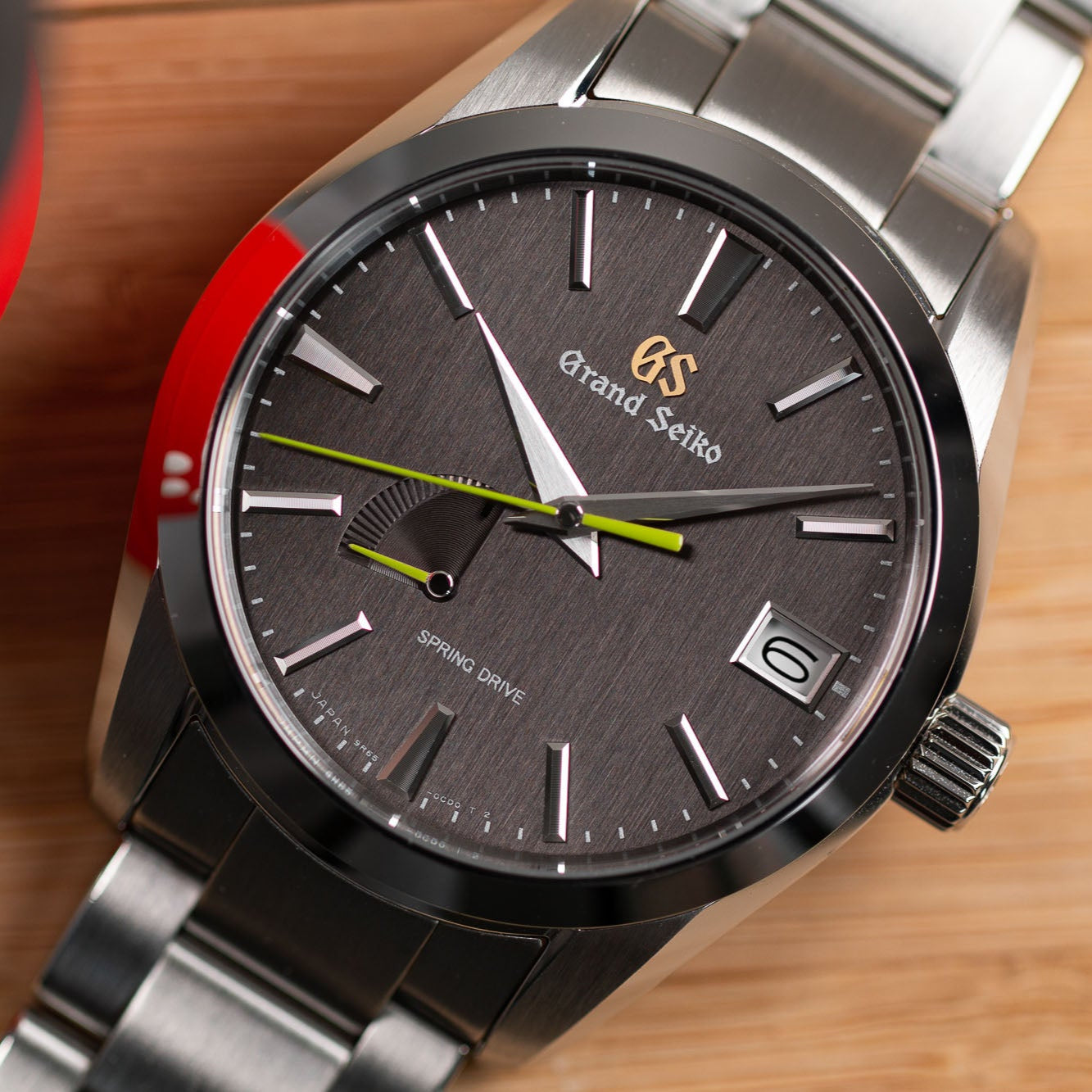 Grand Seiko watch with silver strap and dark dial on a wooden surface