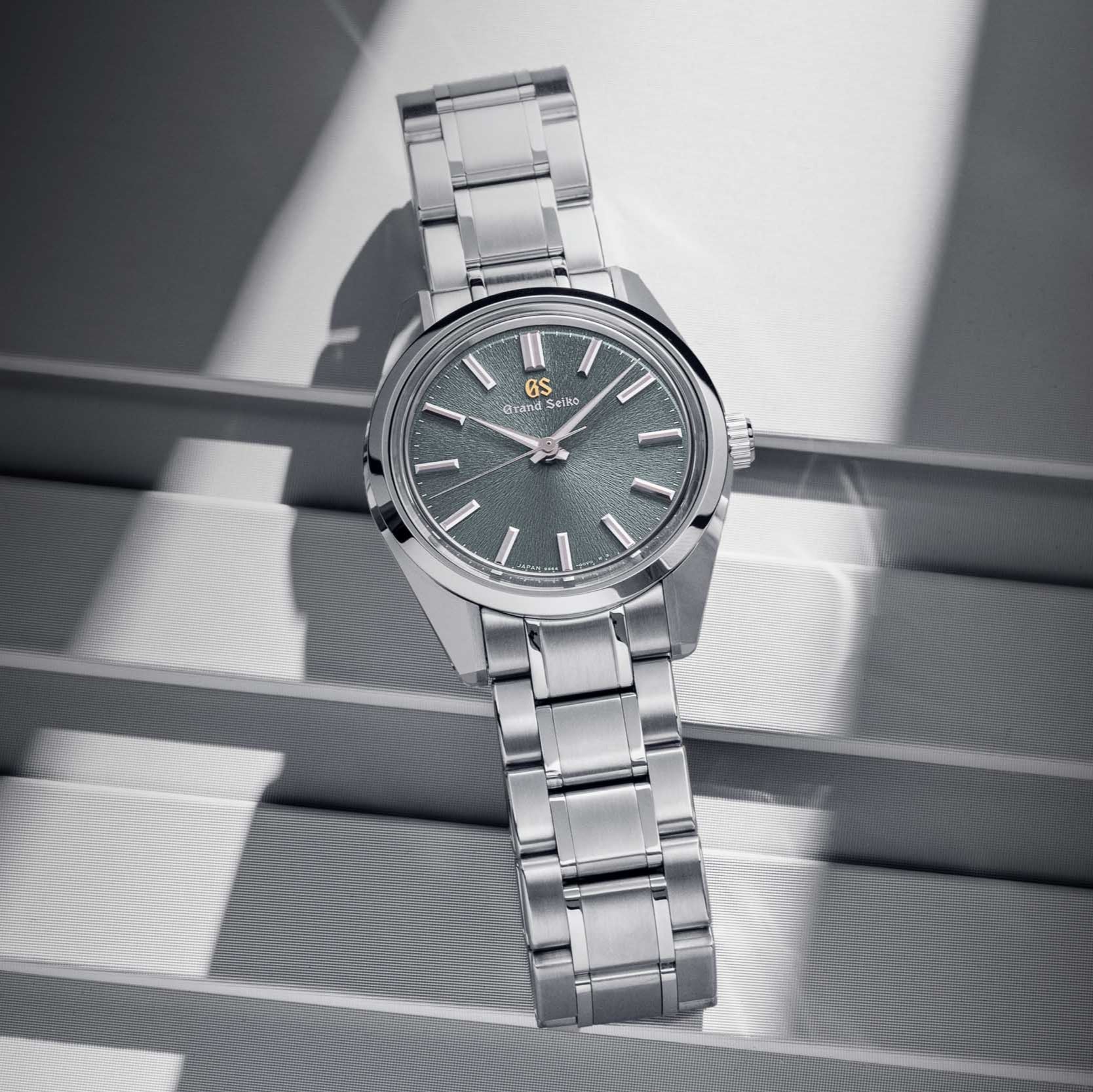 Silver watch with a dark face on a reflective surface