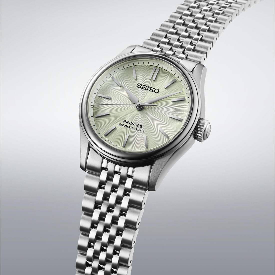 Silver Seiko watch with a light green face on a gray background angled view