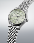 Silver Seiko watch with a light green face on a gray background angled view