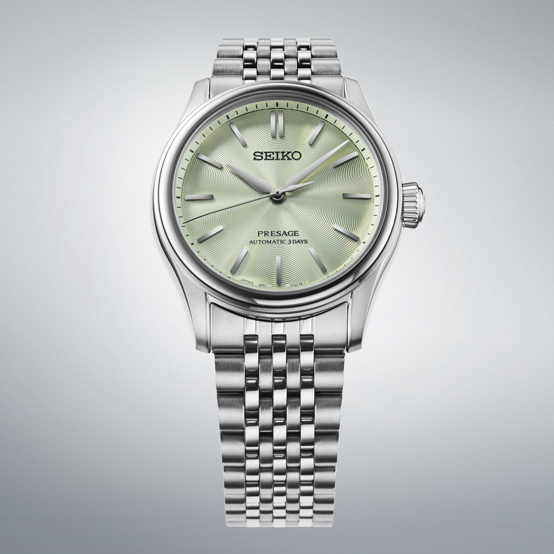 Silver Seiko watch with a light green face on a gray background
