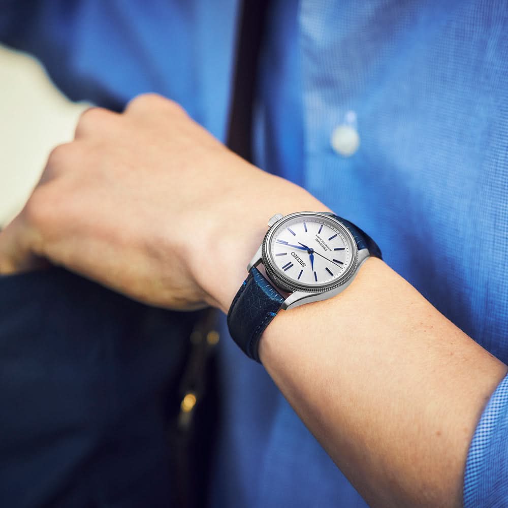 Person wearing a watch with a blue strap against a blurred background