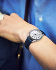 Person wearing a watch with a blue strap against a blurred background