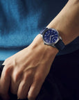 Person wearing a blue wristwatch with a blurred background