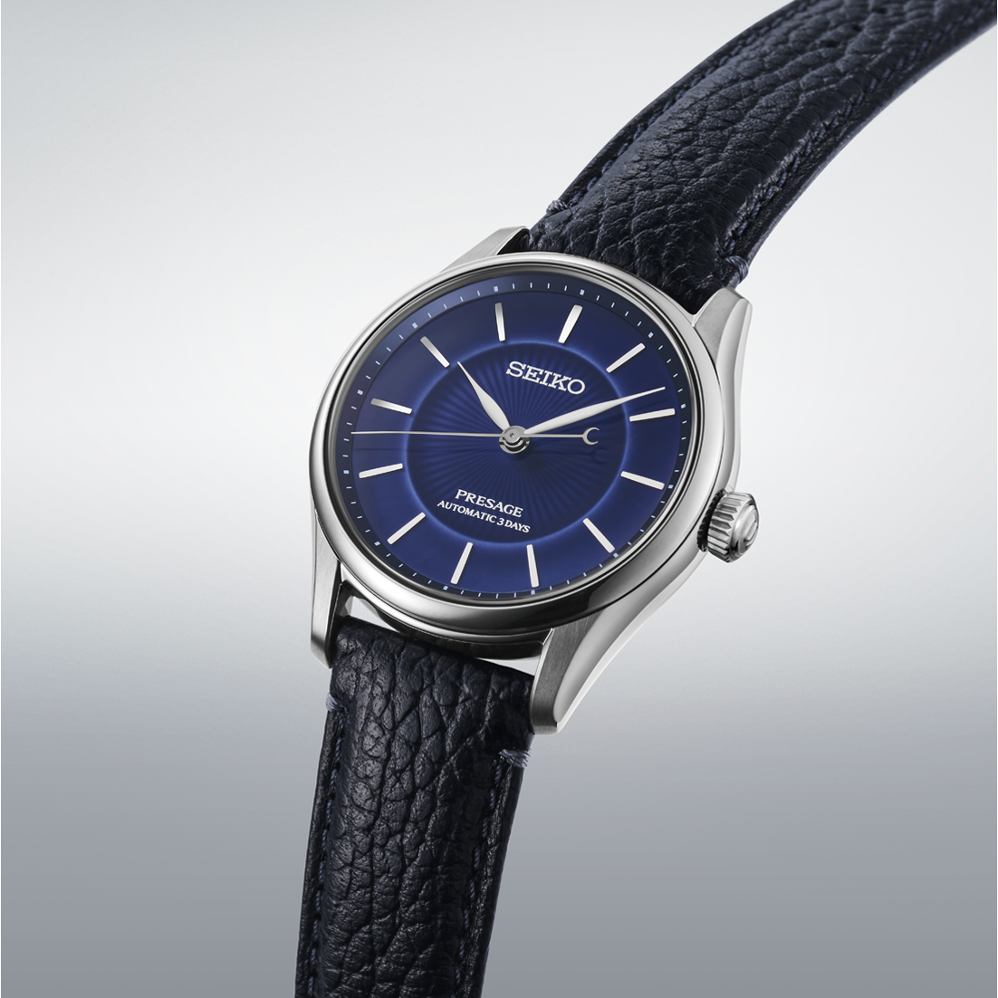 Seiko watch with blue dial and black leather strap on a light gray background- angled