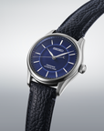 Seiko watch with blue dial and black leather strap on a light gray background- angled