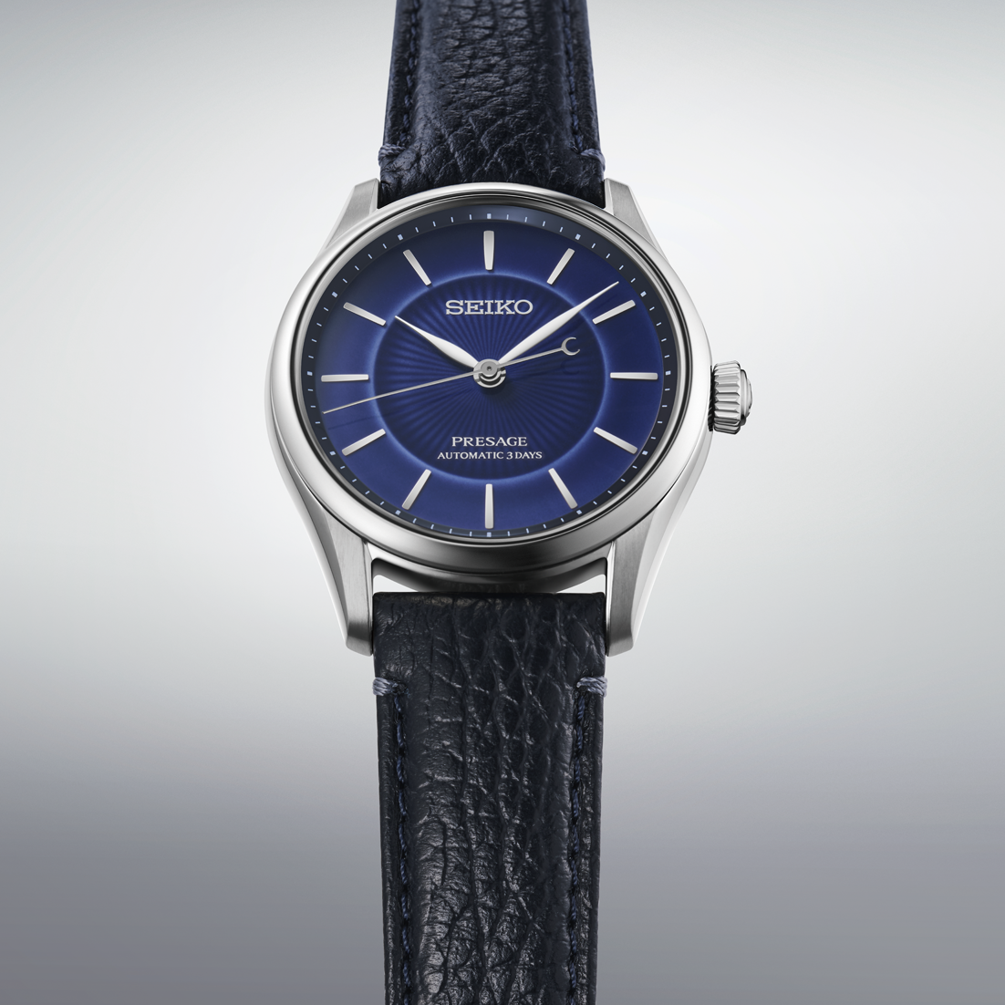 Seiko watch with blue dial and black leather strap on a light gray background