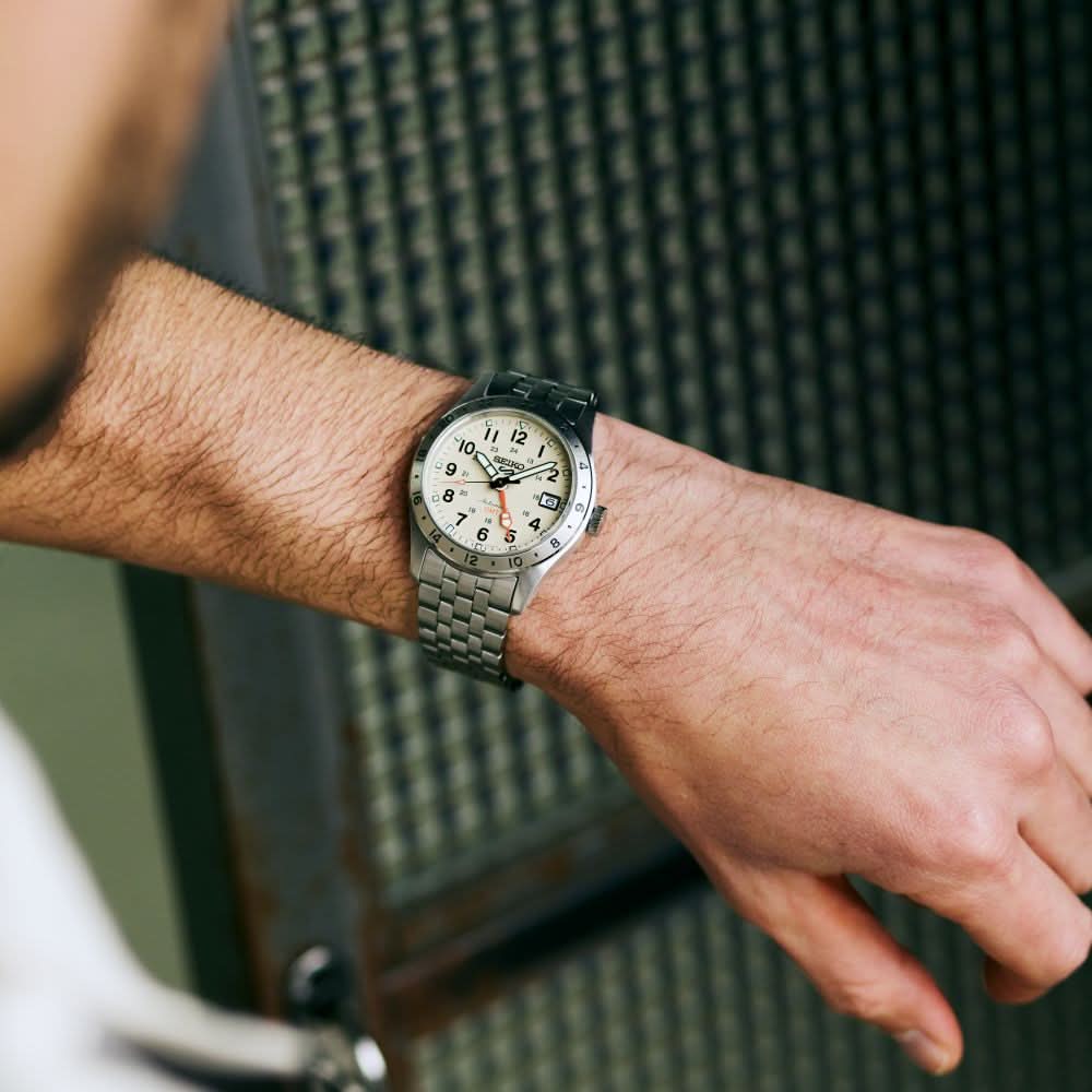 Close-up of a wrist wearing a silver watch with a textured background